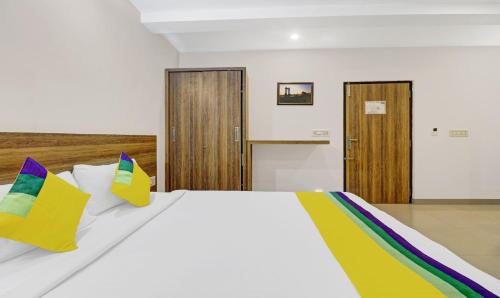 a bedroom with a large white bed with colorful pillows at Itsy Hotels Vijaya Comforts, Coorg in Madikeri