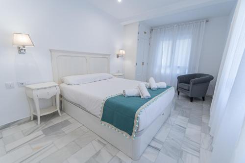1 dormitorio blanco con 1 cama y 1 silla en Apartamento El parador del boticario, en Cádiz