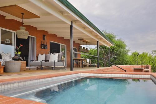 a swimming pool in front of a house at Rockfig Lodge Madikwe in Madikwe Game Reserve