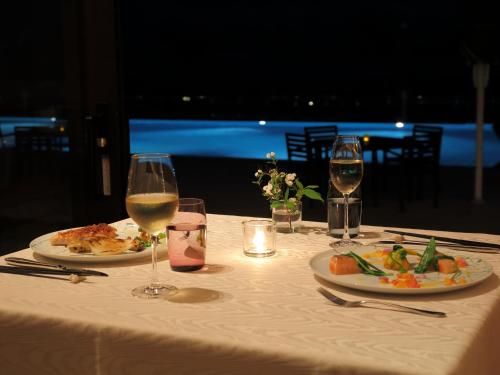 a table with two plates of food and wine glasses at Sankara Hotel & Spa Yakushima in Yakushima