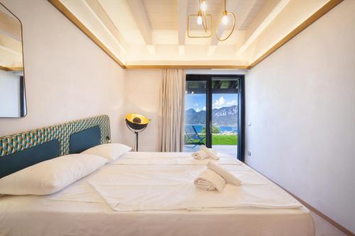 una camera da letto con un grande letto bianco con una finestra di Villa Divina22- APT Icona con piscina e vista lago a Castelletto di Brenzone