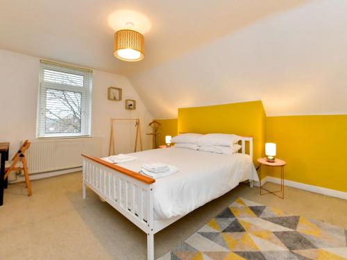- une chambre avec un lit blanc et un mur jaune dans l'établissement Pass the Keys Spacious 3 Bedroom Apartment Close to City Centre, à Cardiff