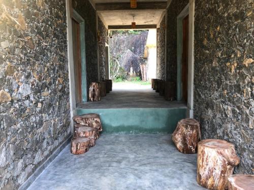 a hallway with stools and a wall with logs at Palabaddala Tea and Eco Lodge in Ratnapura