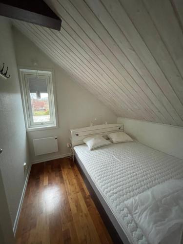 1 dormitorio con 1 cama blanca en una habitación con ventana en Korsanäs, en Listerby