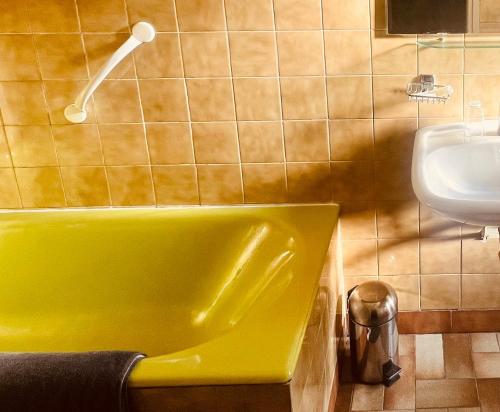 La salle de bains est pourvue d'une baignoire verte et d'un lavabo. dans l'établissement Hotel Camelia, à Boulogne-Billancourt