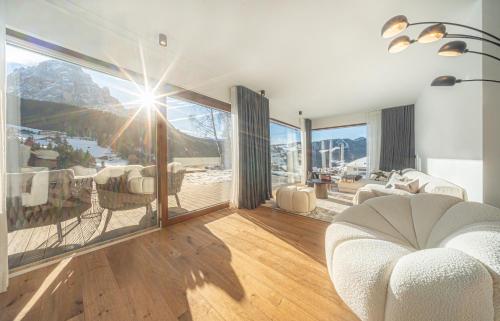 a living room with a white couch and large windows at Villa Carolina in Selva di Val Gardena