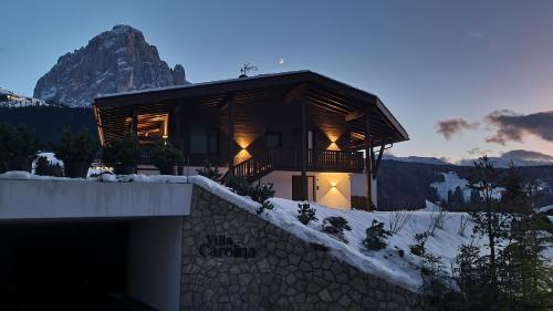 a building in the snow with a mountain in the background at Villa Carolina in Selva di Val Gardena