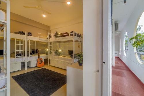 a bedroom with white bunk beds and a guitar at Zostel Hyderabad in Hyderabad