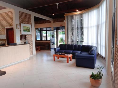 a living room with a blue couch and a table at Silvestre Praia Hotel in Imbituba