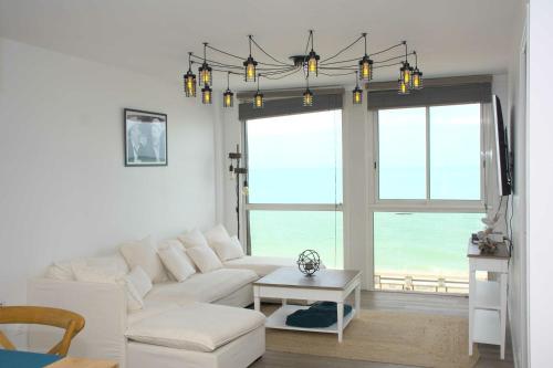 a living room with a white couch and a chandelier at Les pieds dans l eau à Fécamp vue mer in Fécamp