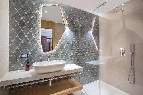 ein Bad mit einem Waschbecken und einer Dusche mit einem Spiegel in der Unterkunft Villa Divina - APT Prima con piscina e vista lago in Castelletto di Brenzone