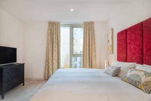 een slaapkamer met een groot bed en een televisie bij Austin David Apartments Royal Wharf in Londen
