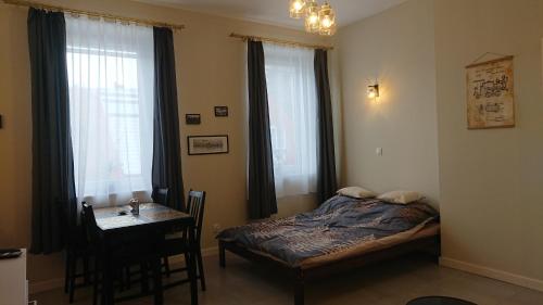 ein Schlafzimmer mit einem Bett und einem Tisch und Fenstern in der Unterkunft Apartament Pod Semaforem Duszniki-Zdrój in Duszniki-Zdrój