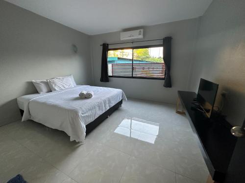 a bedroom with a bed and a television and a window at Pine Home in Krabi town