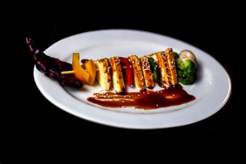 a plate of food with sauce and vegetables on a table at Beverly Hotel in Chennai