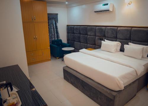 1 dormitorio con 1 cama grande y 1 silla azul en Kawruky Hotel Benin, en Benin City
