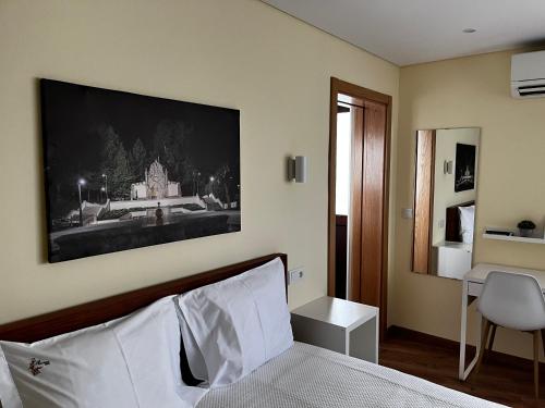 a bedroom with a bed with a picture on the wall at Aliança Alojamento Local in Guarda