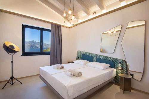 a bedroom with a bed with a mirror and a lamp at Villa Divina - APT Divina con piscina e vista lago in Castelletto di Brenzone