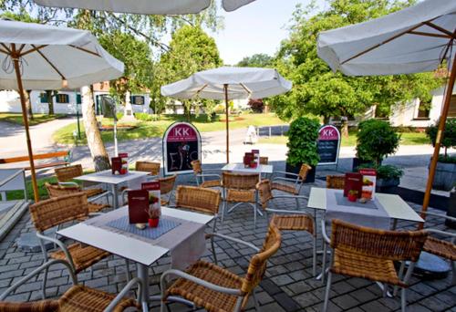 an outdoor patio with tables and chairs and umbrellas at Kaplan am Kurpark in Bad Tatzmannsdorf