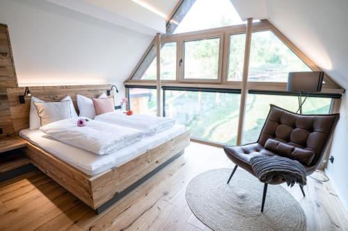 a bedroom with a bed and a chair and a window at Kellerstöckl Heuberger in Eltendorf