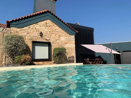 a house with a swimming pool in front of a building at Quinta do Tojal - Tourism immersed in nature! in Vila Maior