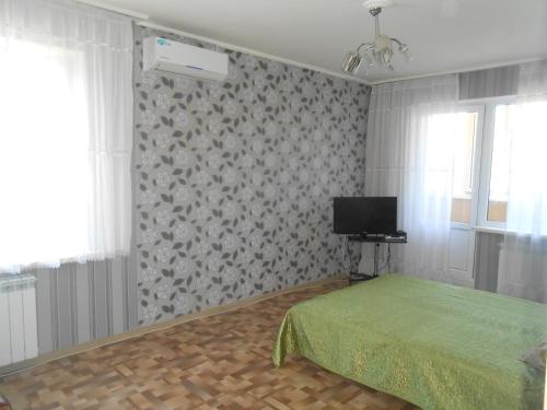 1 dormitorio con 1 cama y TV en la pared en Уютная однокомнатная квартира, en Almaty