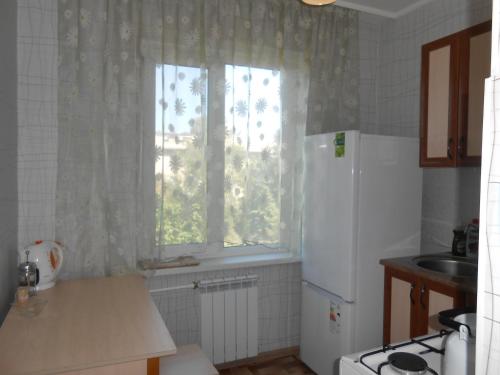 cocina con nevera blanca y ventana en Уютная однокомнатная квартира, en Almaty