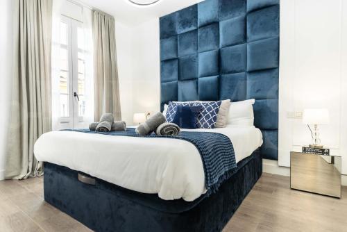 1 dormitorio con 1 cama grande y cabezal azul en Contemporary lujo duplex in the heart of Malaga, en Málaga