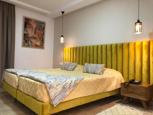 ein Schlafzimmer mit einem großen Bett mit einem gelben Kopfteil in der Unterkunft Larimar Hôtel Sfax in Sfax