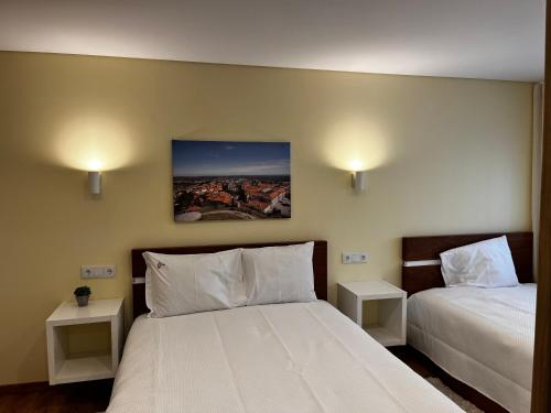a bedroom with two beds and two nightstanduments at Aliança Alojamento Local in Guarda