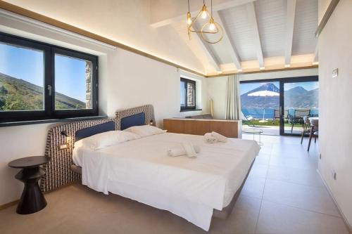 una camera da letto con un grande letto bianco e grandi finestre di Villa Divina22-APT Unica-Con piscina e vista lago a Castelletto di Brenzone