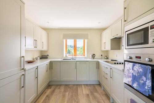 a white kitchen with white cabinets and a window at The Granary at Hawkhurst in Craven Arms