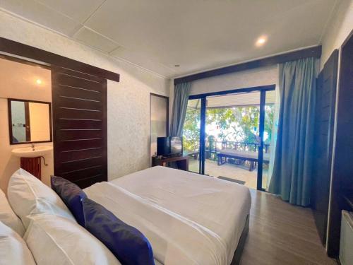 a bedroom with a large bed and a sliding glass door at Koh Kwang Beach Resort in Ban Ko Kwang