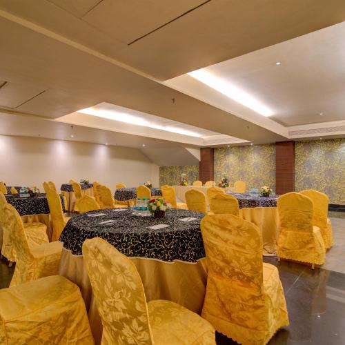 una sala de conferencias con mesas y sillas amarillas, una mesa y un sillón en Godwin Candolim,Goa, en Candolim