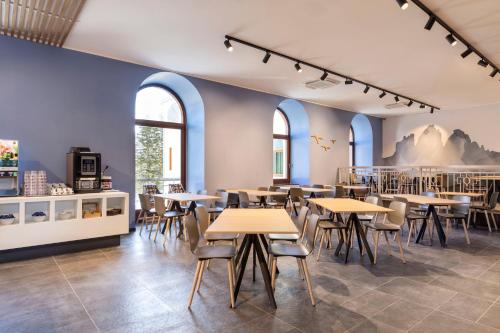un restaurant avec des tables, des chaises et des fenêtres dans l'établissement B&B Hotel Passo Tre Croci Cortina, à Cortina dʼAmpezzo