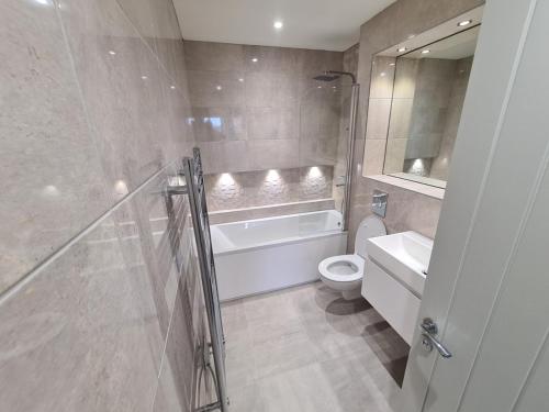 a bathroom with a tub and a toilet and a sink at Jasmin Apartments - Luxury 1 & 2 Bedroom units with Free Parking in Bushey