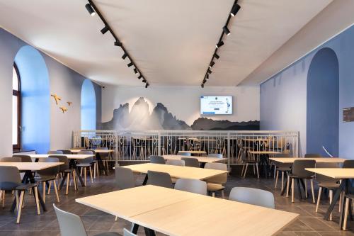 una sala da pranzo con tavoli, sedie e schermo di B&B Hotel Passo Tre Croci Cortina a Cortina dʼAmpezzo