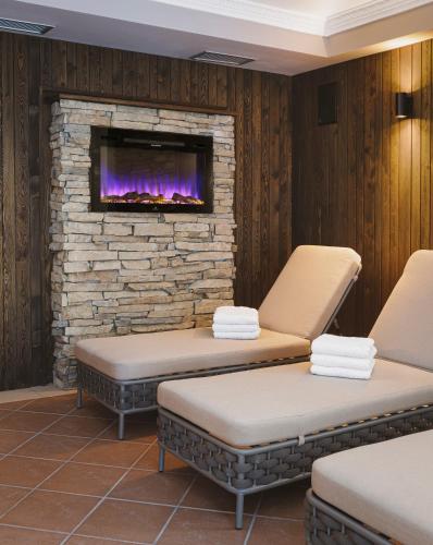 two massage chairs in a waiting room with a fireplace at Aparthotel Familiaris - Family Apartments - Pools & Spa in Dolomites in Valdaora