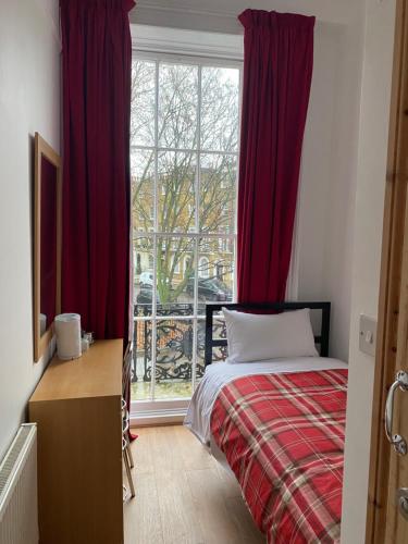 a bedroom with a bed and a window with red curtains at 27 Argyle Square in London