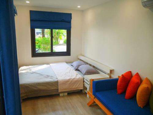 ハイフォンにあるCửa Biển Homestayのベッドルーム1室(ベッド1台、窓、ソファ付)