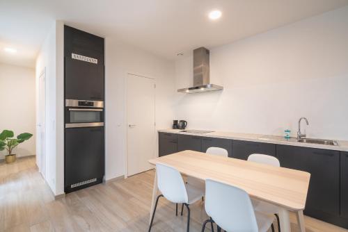 a kitchen with a wooden table and white chairs at Opera Square Apartments in the Center of Antwerp in Antwerp