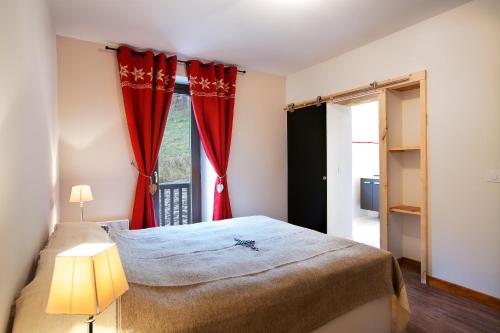 um quarto com uma cama e uma janela com cortinas vermelhas em LE CHAMOIS LODGE em Hauteluce