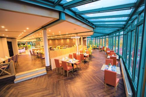 a dining room with tables and chairs and windows at Best Western Parkhotel Brehna-Halle in Brehna