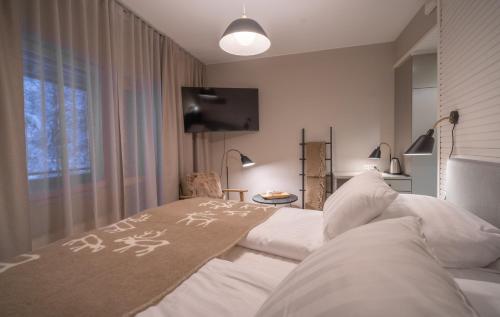 een slaapkamer met een bed met een deken erop bij Wilderness Hotel Juutua in Inari
