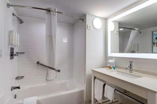 a white bathroom with a tub and a sink at Clarion Pointe Galveston Seawall in Galveston