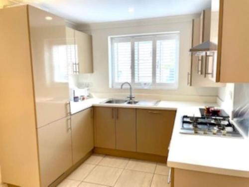 a kitchen with white cabinets and a sink and a window at Modern Town House near Oxford - 3 double bedrooms in Witney