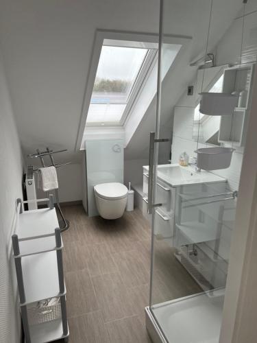 łazienka z toaletą, umywalką i oknem dachowym w obiekcie Strandnahe Ferienwohnungen Duhnen inkl Fahrrädern Cuxhaven w mieście Cuxhaven