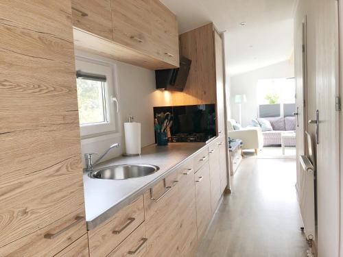 a kitchen with wooden cabinets and a sink at Chalet 538 op Recreatiepark De Wielen in Sint Maarten