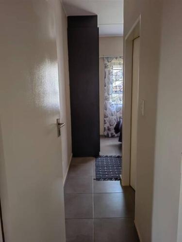 a hallway with a black door and a tile floor at Modern 2 bedroom at Waterfall Ridge-Midrand in Midrand