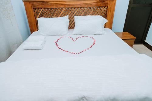 a white bed with a heart drawn on it at Kisanga Homestay in Moshi